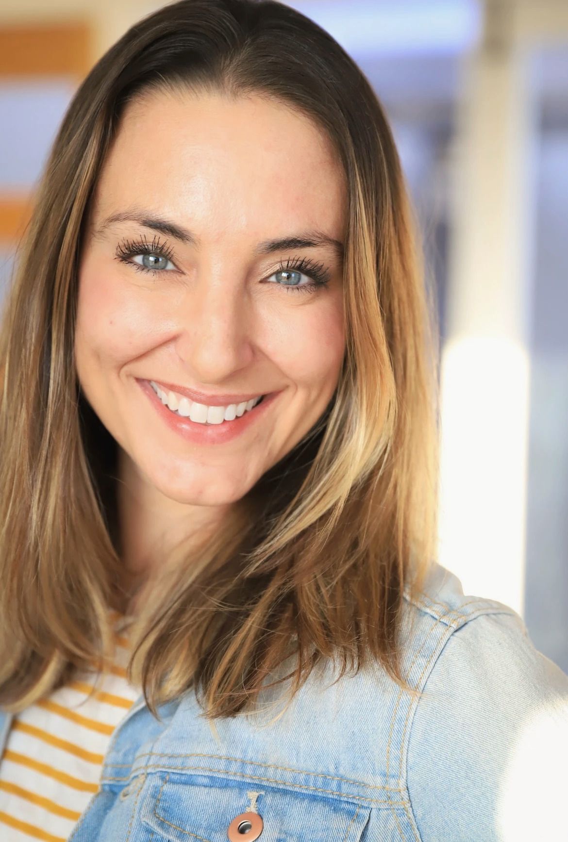 Portrait of Cara, smiling, in a denim jacket.